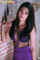 Leaning against wall long hair trailing over her purple dress