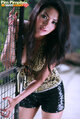 Pim pimpilai leaning against metal gate long hair wearing shorts painted fingernails