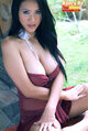 Seated with legs spread hands resting on her thighs big tits erupting from her dress