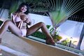 Sitting on edge of pool wearing bikini exposing big breast legs spread