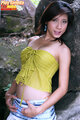Leaning against rock wearng green top thumbs in short skirt