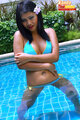 Standing in pool arms folded wearing bikini