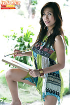 Balancing canvas on her knee holding paint brush