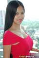 Standing in front of window long hair over her shoulder wearing red dress