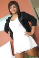 Standing with hands on hips wearing black jacket in white dress